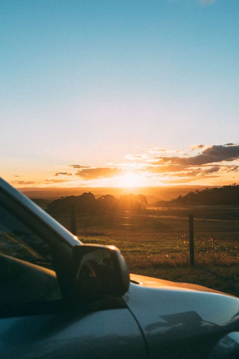 trickle charger golden hour photography of vehicle park near fence