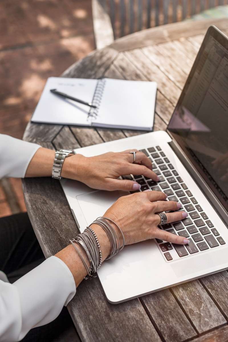 Payroll Software person typing on MacBook Pro on brown wooden table during daytime photo