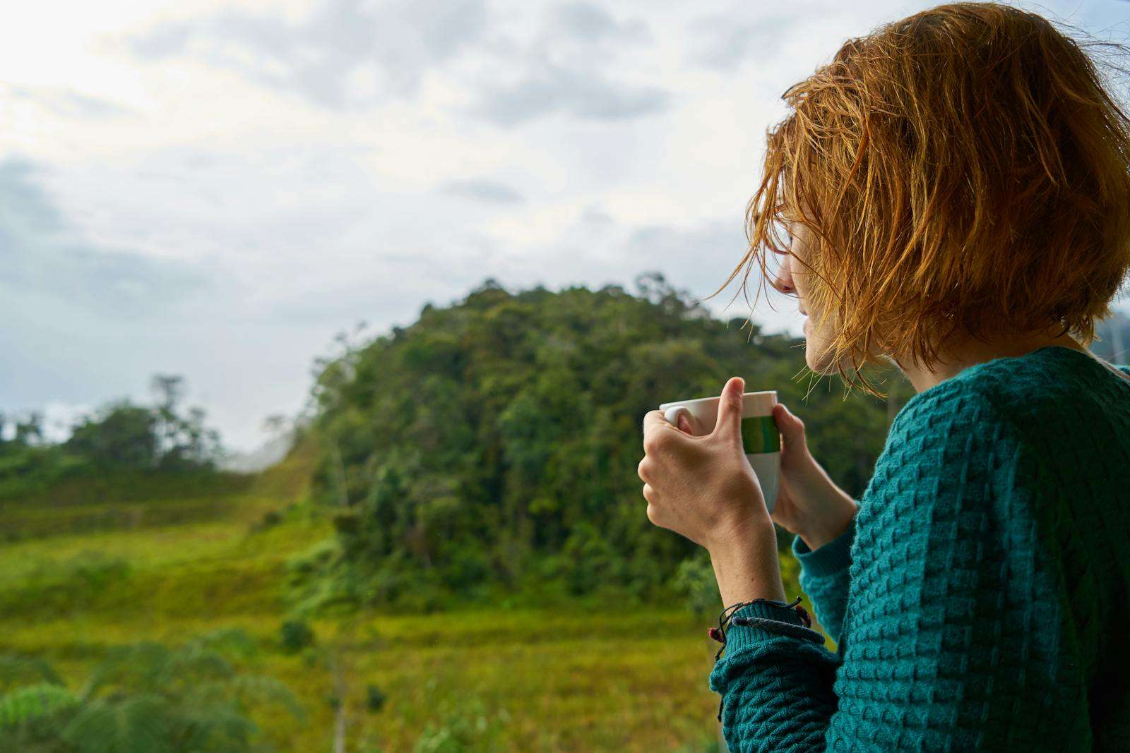 How to Find a Way Forward When Life Feels Too Heavy A woman with short hair enjoys a hot drink outdoors in Pahang, Malaysia, surrounded by lush greenery.