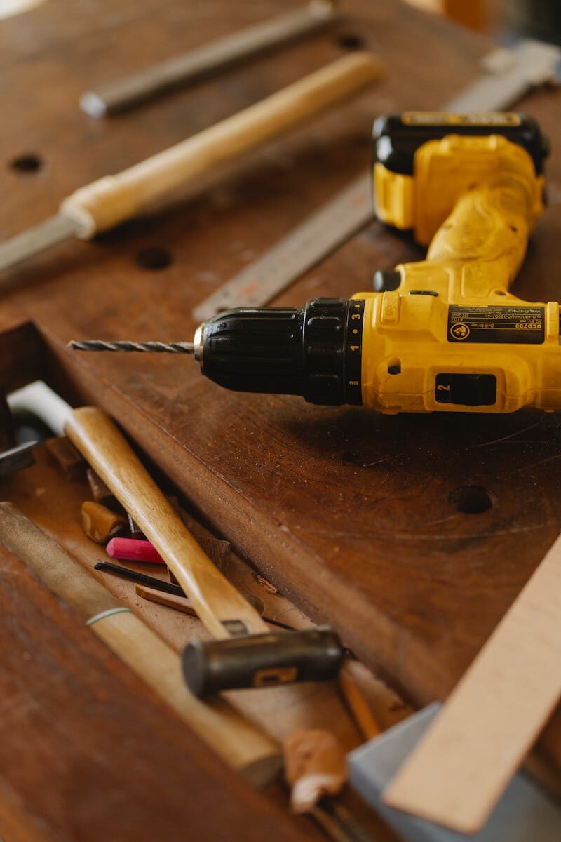 smart ways to save money when buying power tools From above of contemporary screwdriver with drill near hammer and tools on wooden desk