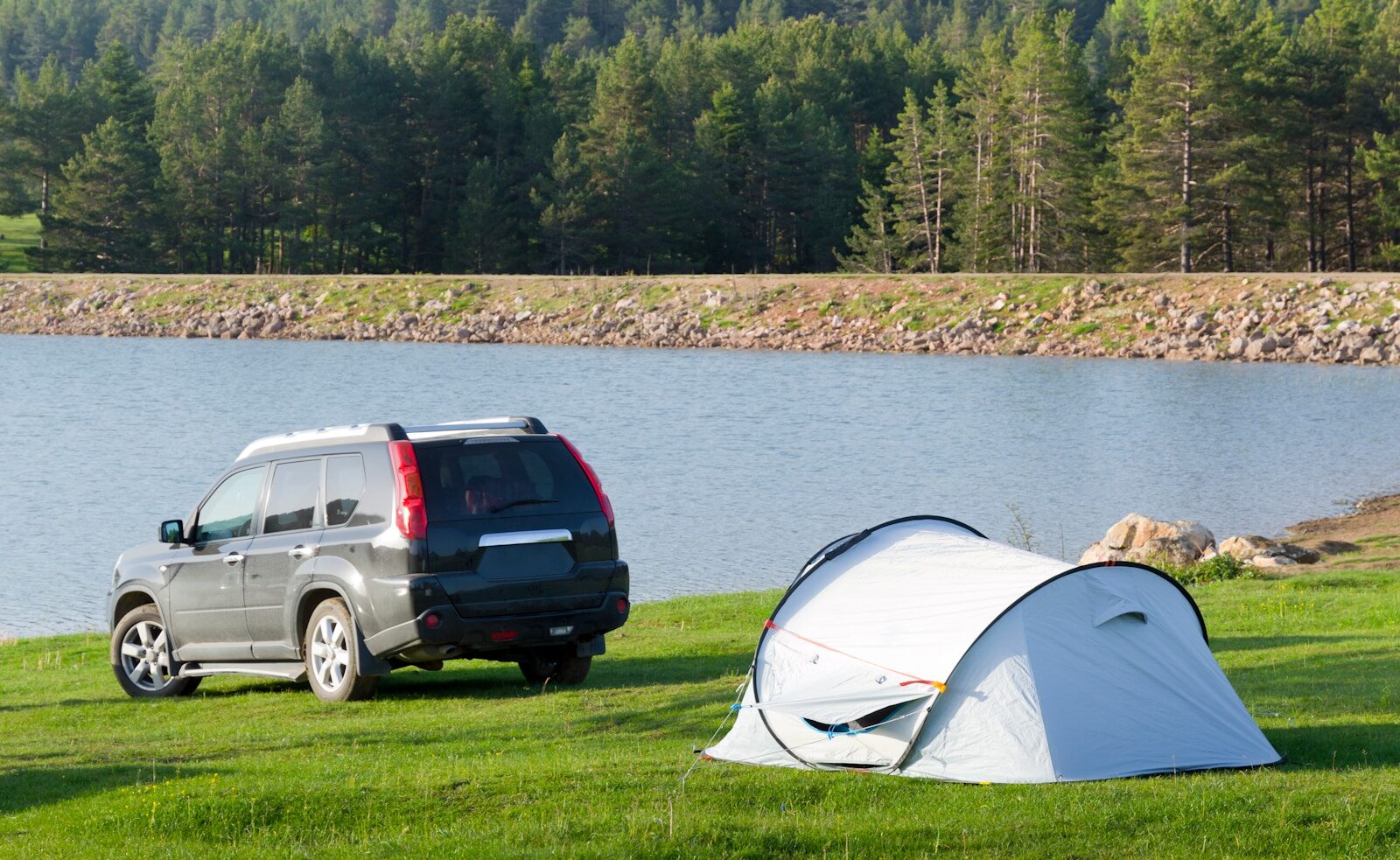 5 Essential Elements of a Highly Efficient Off-Grid Camping Setup Tent and car parked by a calm lake