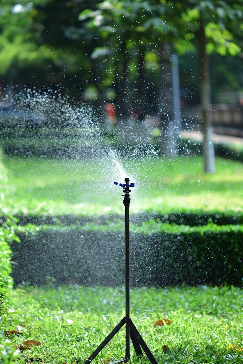 Water-Smart Irrigation Techniques for a Healthier Lawn Sprinkler watering a lush green garden lawn on a sunny day, creating a refreshing scene.