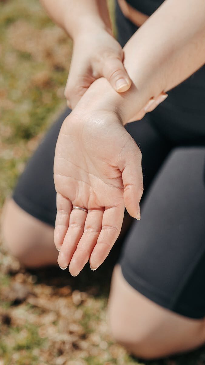 Recovering from a Hand Injury: Timeline and Tips for Faster Healing Close-up of a woman's hand holding her wrist outdoors, symbolizing injury or pain relief.