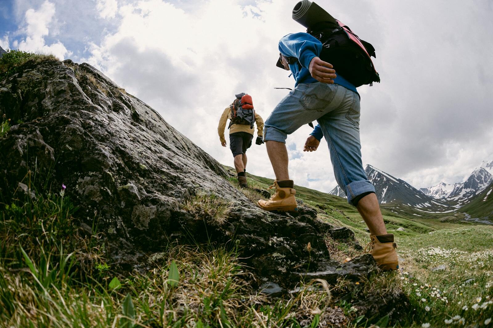 Walking boots Two hikers climb a rocky trail in picturesque mountain scenery, signaling an adventurous expedition.