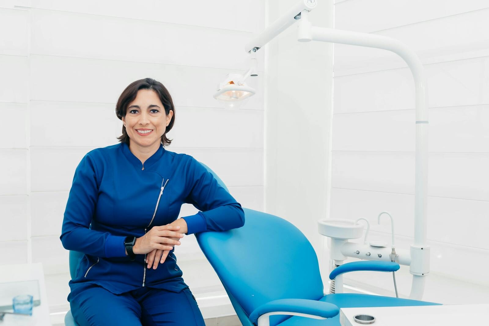 How Oral Health Affects Overall Wellness Smiling female dentist sitting in a modern clinic, ready for patients