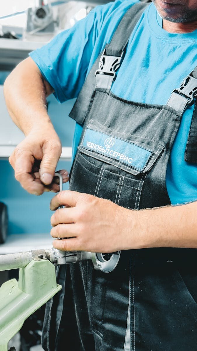 Why Low Water Pressure is More Than Just a Nuisance for Your Home Close-up of a plumber in blue uniform working on a pipe repair with a wrench.
