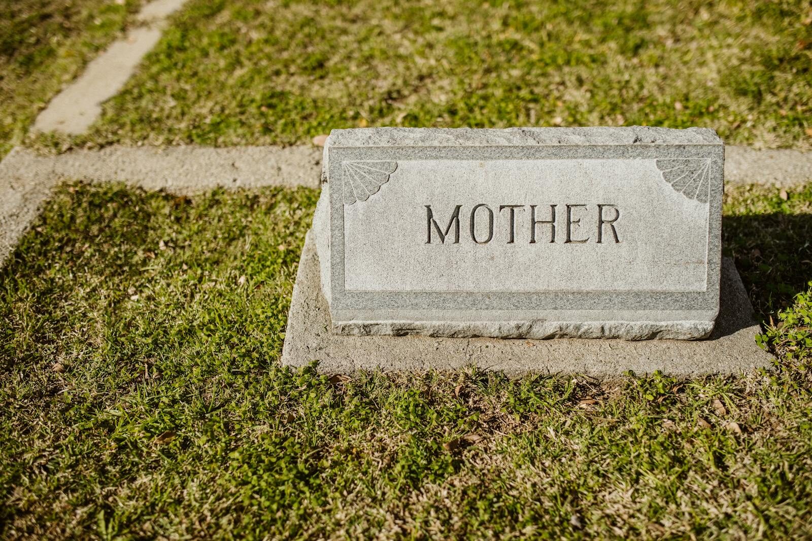 How to Choose the Best Ledger Headstones for a Loved One Gravestone in cemetery engraved with the word 'Mother' on grass.