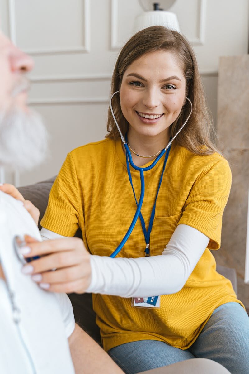 Comprehensive Guide to Intensive Outpatient Programs (IOPs) Young female healthcare worker in yellow shirt listens to patient with a stethoscope.