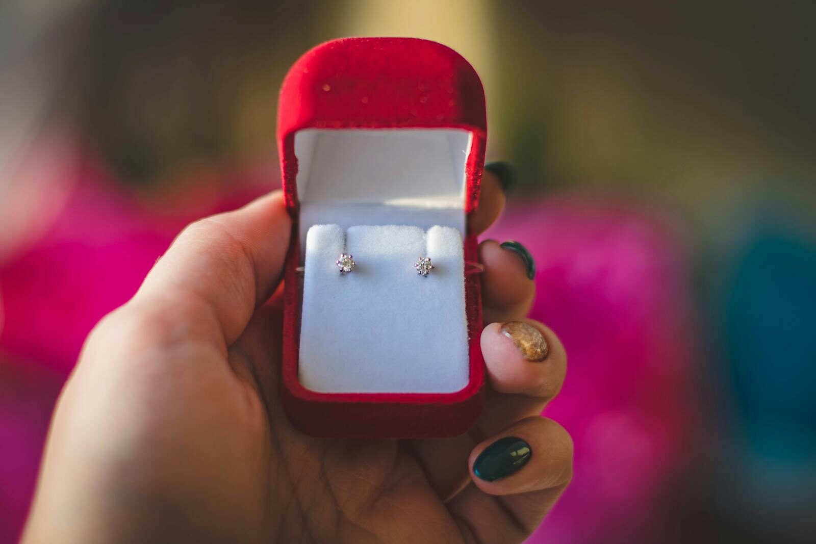Why Diamond Stud Earrings Work for Every Age and Style: 5 Key Reasons Elegant diamond earrings displayed in a luxurious red velvet box held by a hand.