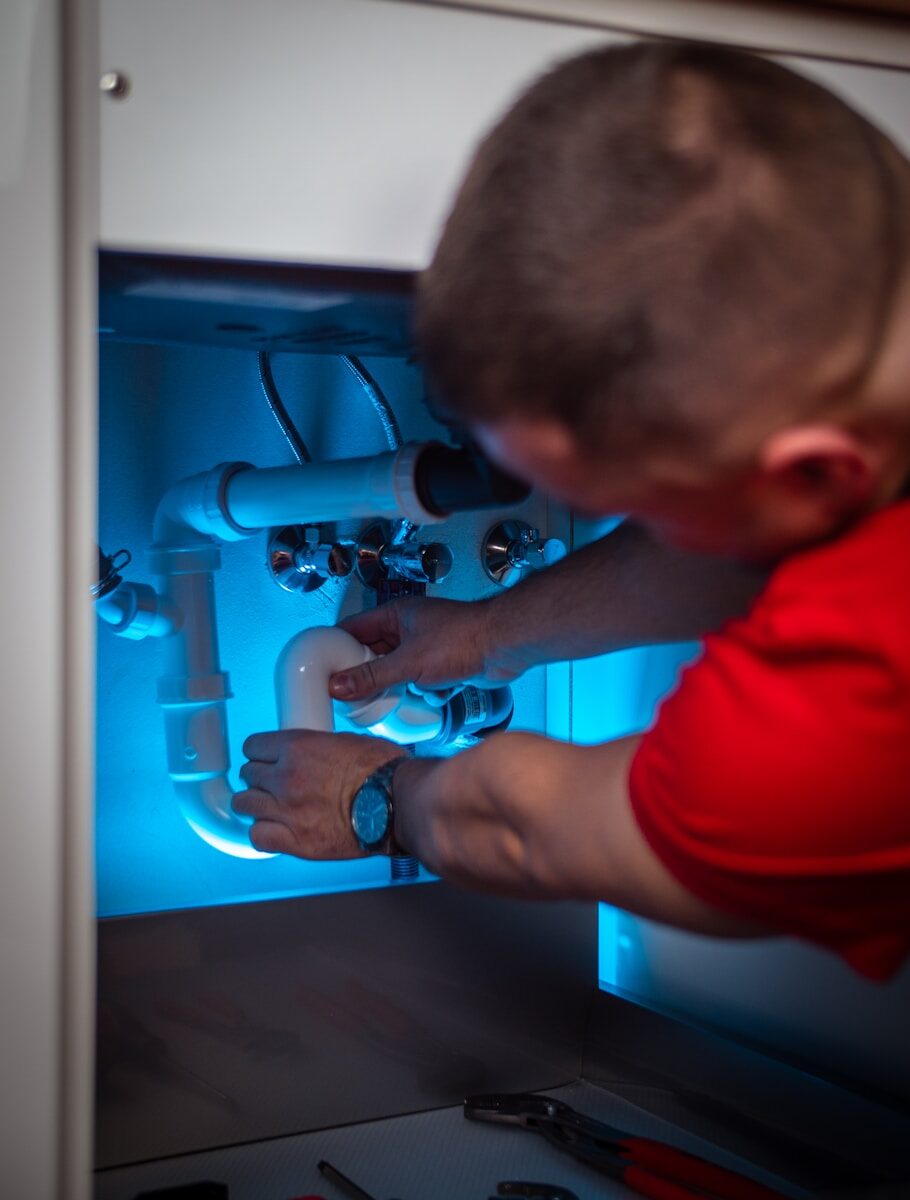 Emergency Plumbing Solutions: Quick Guide for Accessing A Plumber Near Me a man working on a pipe in a cabinet