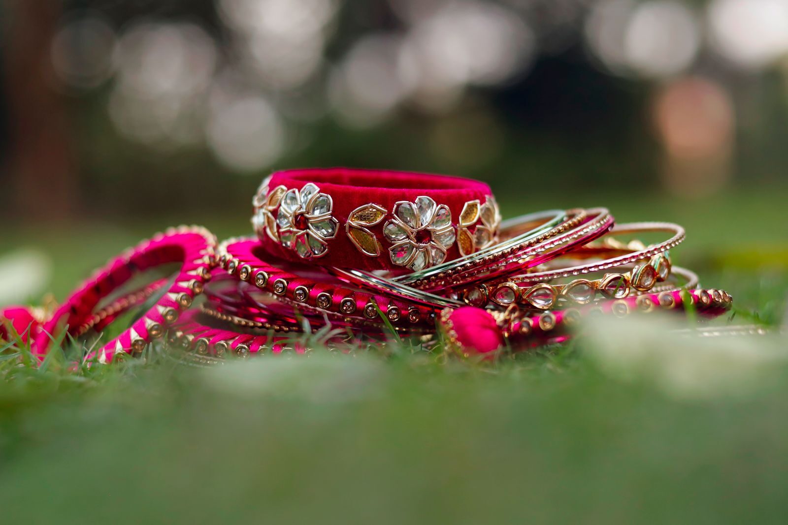 Why Handcrafted Jewellery Is the Ultimate Statement of Personal Style A close-up of traditional red and gold bangles resting on grass, showcasing intricate designs.