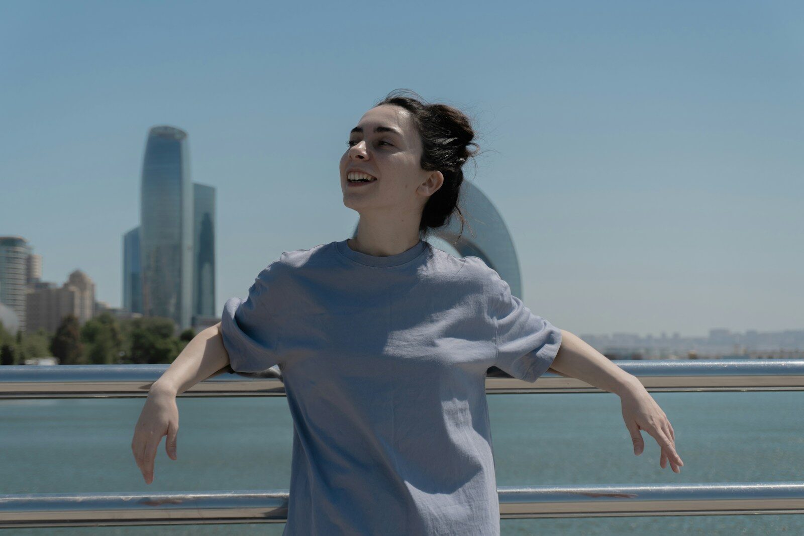 How a Smile Transformation Can Boost Your Confidence Woman smiles, arms out, overlooking a cityscape.