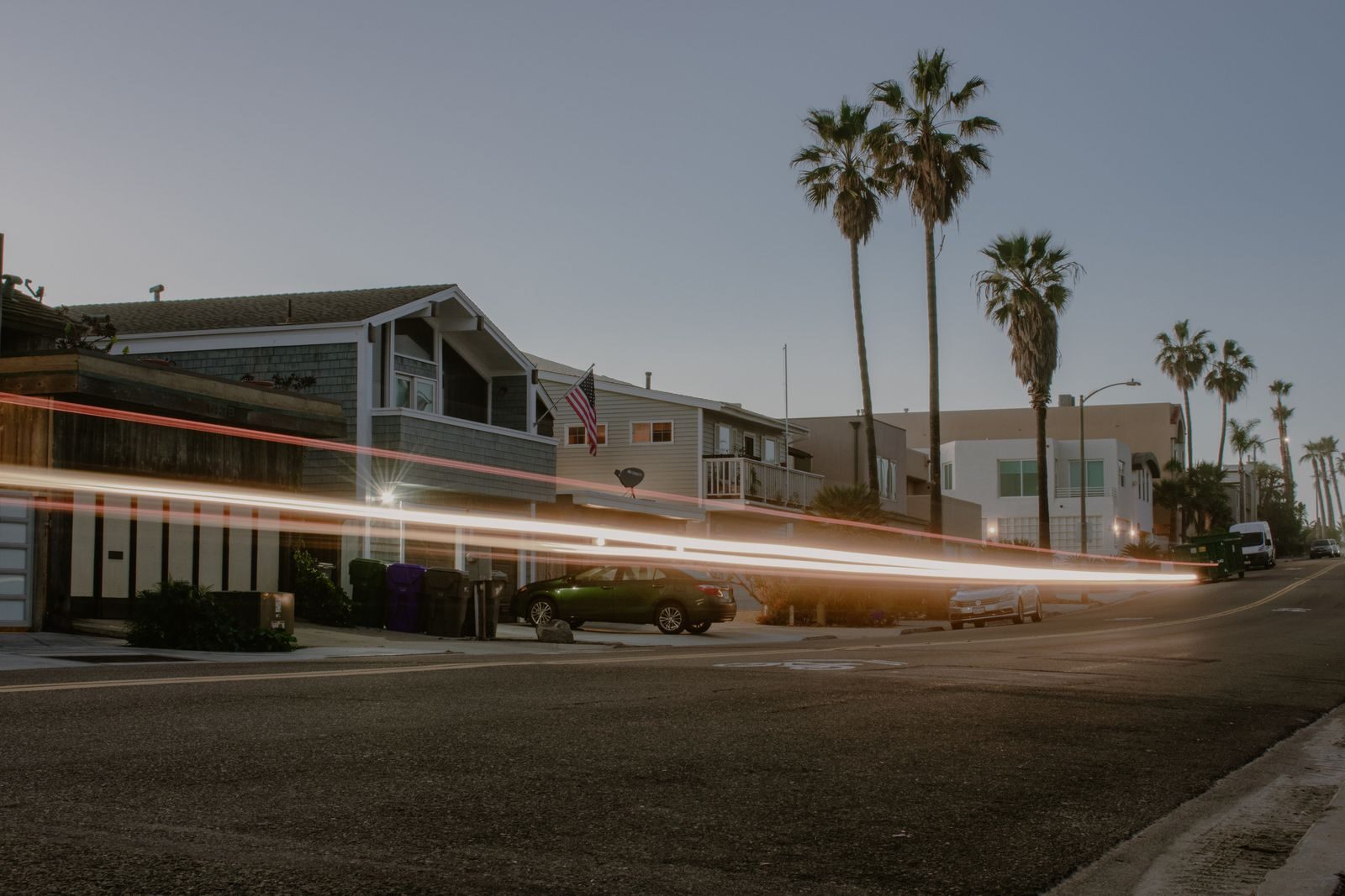 Selling Your House for Cash in Long Beach: The Ultimate Guide Palm-lined street with light trails from cars at twilight, showcasing modern coastal homes.