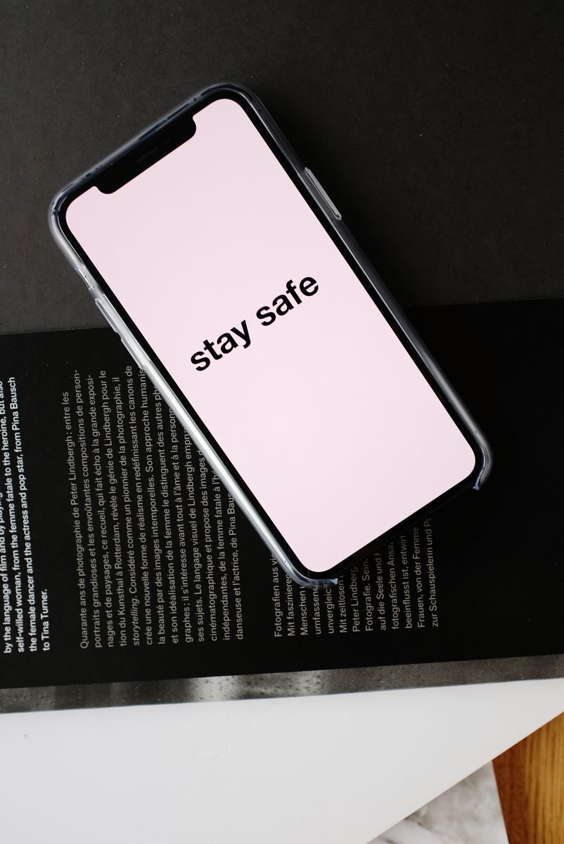 Small Digital Habits That Can Make Everyday Life Easier Top view of modern mobile phone with pale pink screen and STAY SAFE inscription placed on open magazine with black page and white letters during COVID 19 pandemic