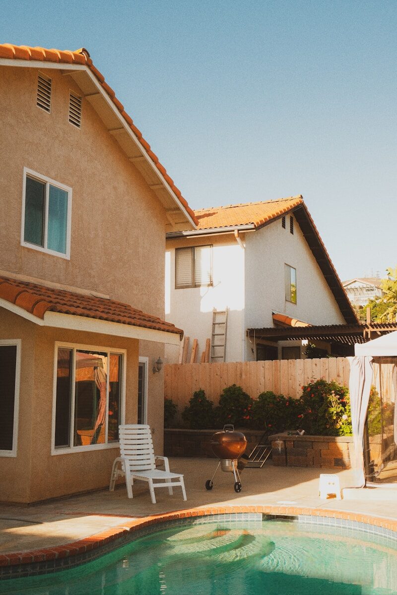 Buying a Home in Fredericksburg, VA: A Comprehensive Guide for Homebuyers Houses with red roofs, swimming pool, and backyard barbecue.