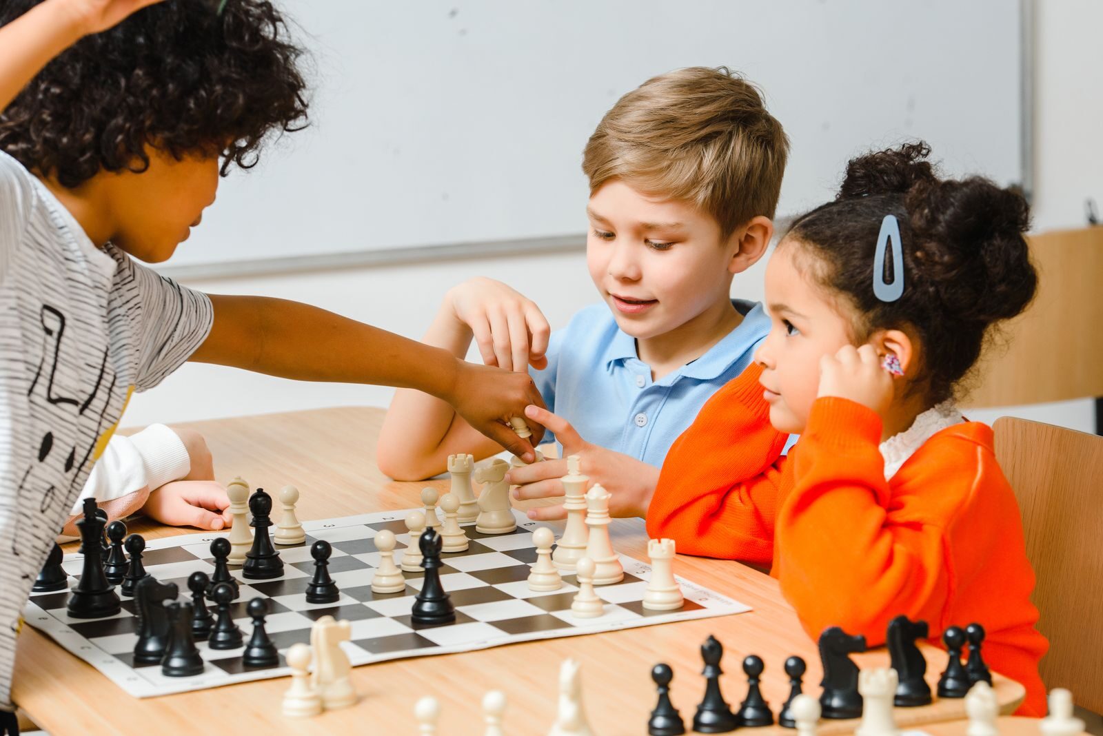 7 Things Parents Should Look for When Choosing an After-School Program Group of diverse children engaged in a chess game, enhancing strategy skills.