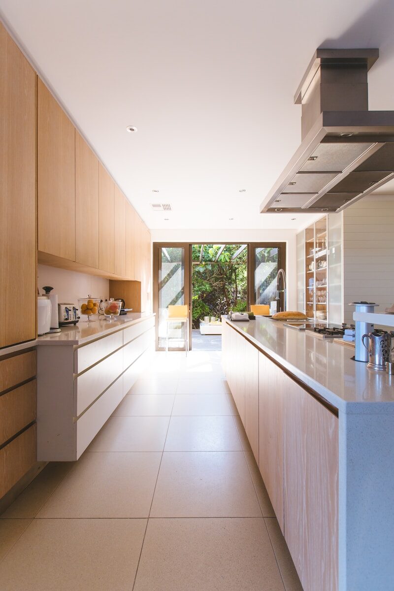 A Practical Guide to Kitchen Lighting and Cabinet Hardware white wooden kitchen island and cupboard cabinets near glass panel door