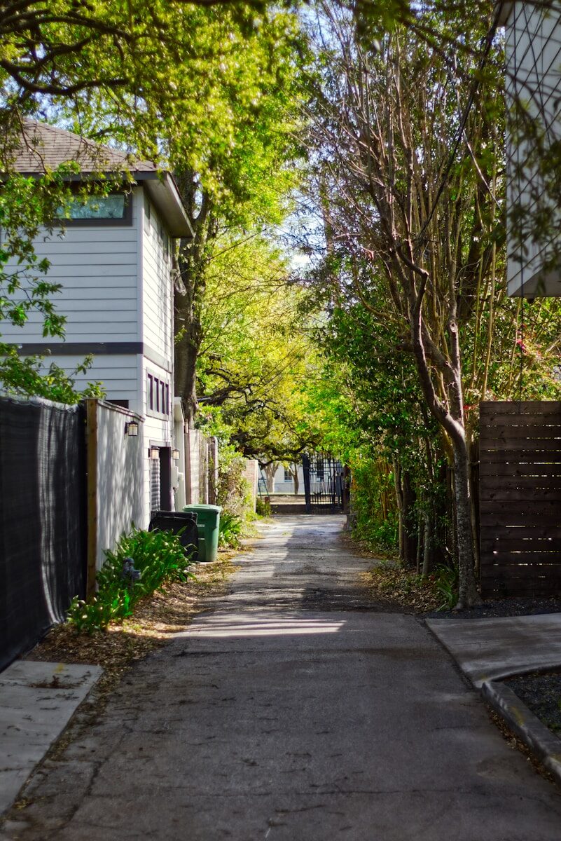 The Consequences of Leaving a House Unoccupied in Texas A narrow residential alleyway lined with trees and houses.