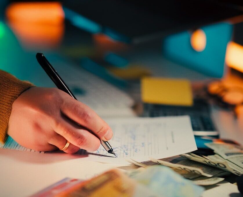 6 Best Out-of-State 529 Plans for Iowa Residents Hand writing on paper with euro banknotes and dollar bills.