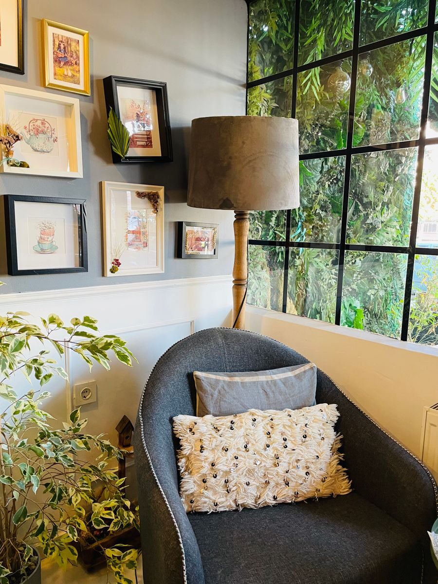Creating a Cozy Home Retreat for Better Well-Being Charming living space featuring an armchair, floor lamp, and framed artwork by a window.