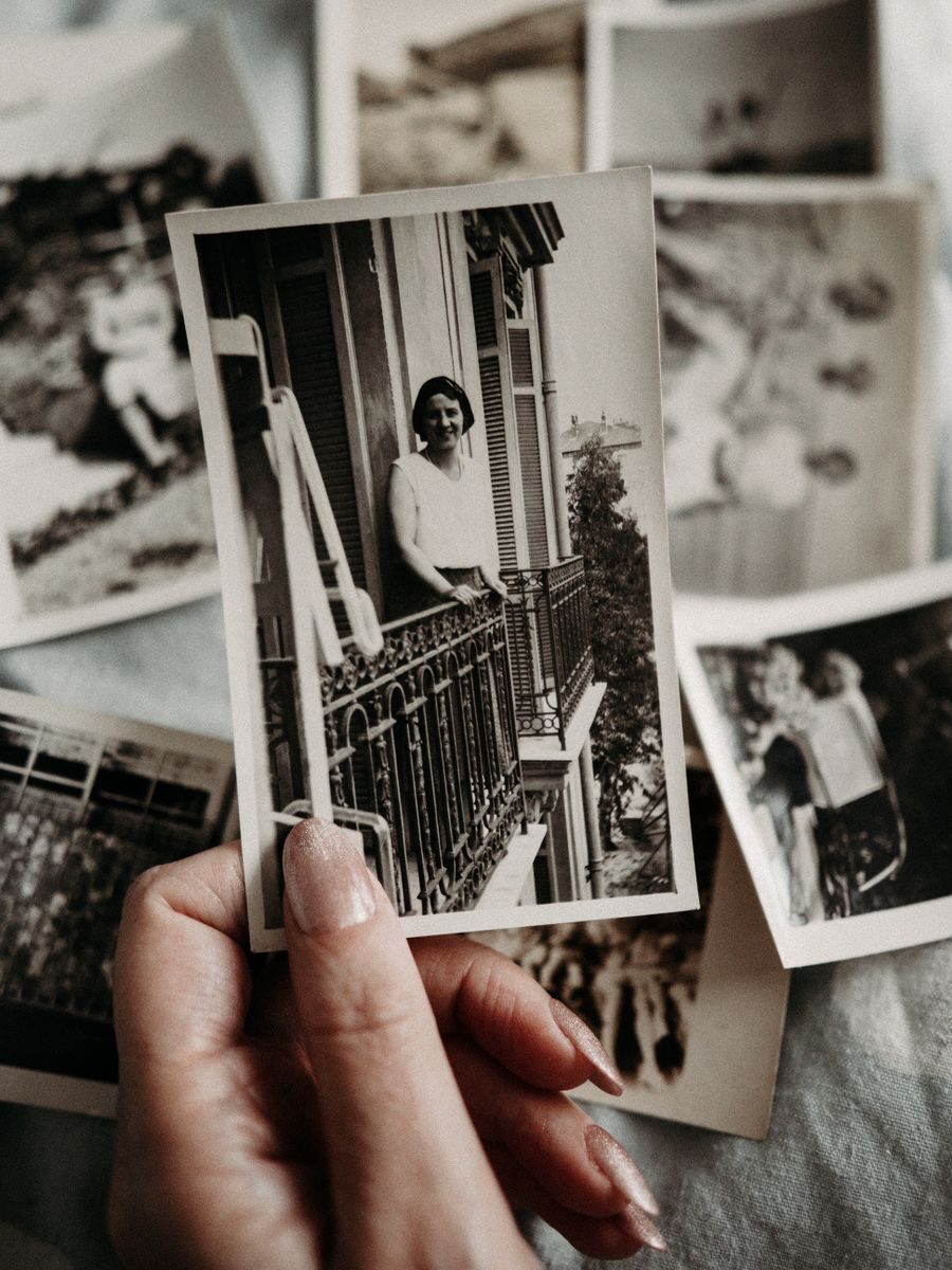 Declutter Death Cleaning Hand holding a collection of vintage black and white photographs, evoking nostalgia and retro vibes.