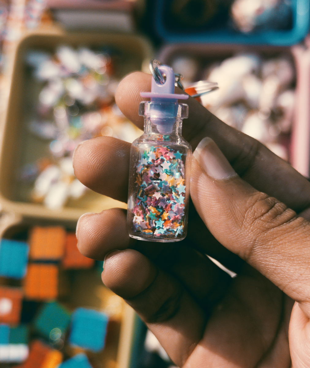 death cleaning declutter Close-up of a hand holding a tiny glass vial filled with colorful stars, perfect for creative projects.