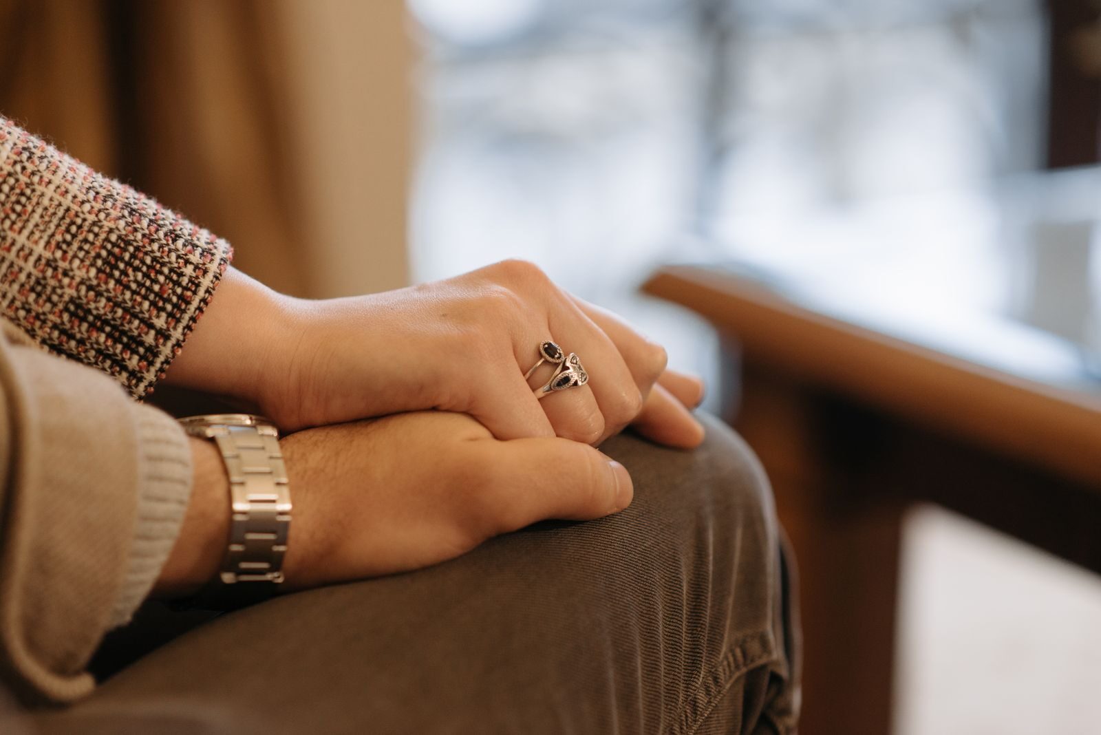 Addiction-Based Bond: Build Sober Stability With Couples Rehab California A close-up view of a couple holding hands, showcasing rings and a wristwatch, indoors.