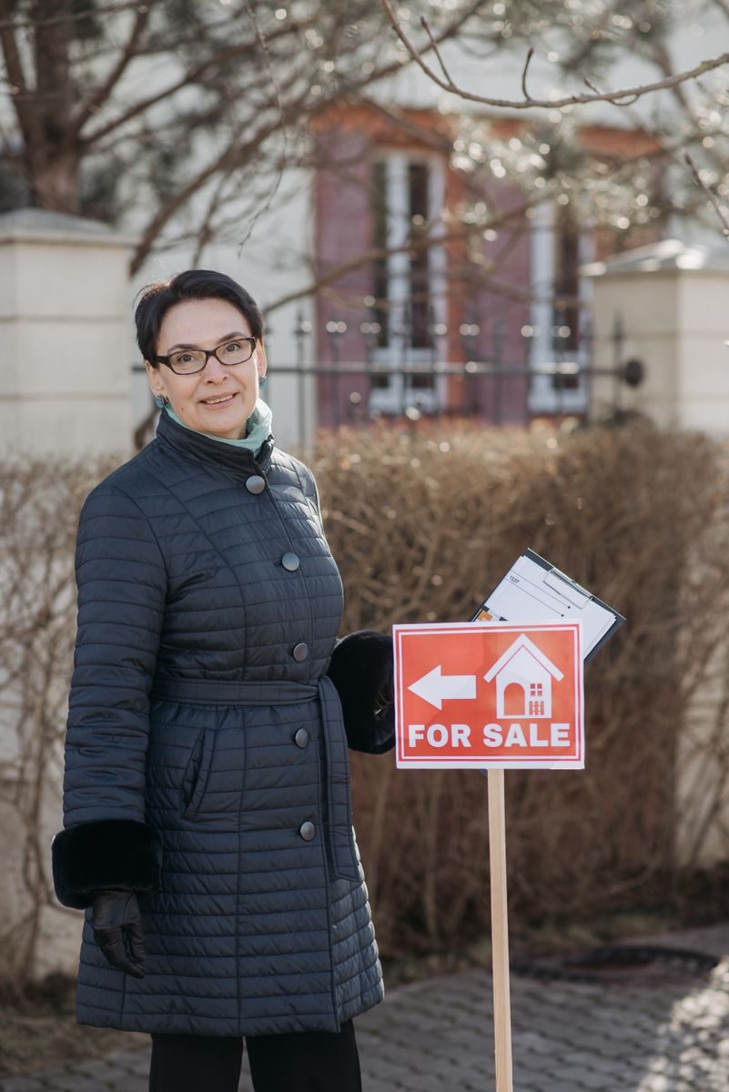 Selling a House Fast in 2026: A Clear Comparison of Cash, Agent, and DIY Options Realtor posing with a for sale sign outside a house, showcasing real estate services.