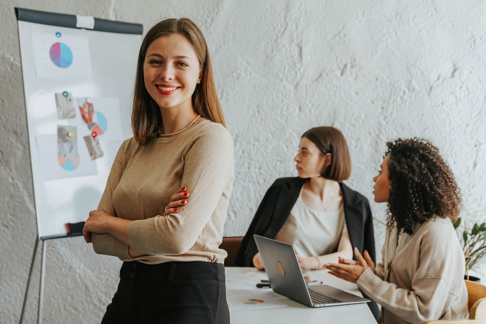 Qualities of the Best Behavioral Health Leaders, According to Charles Nabit Confident woman smiling in a modern office setting with colleagues at work.