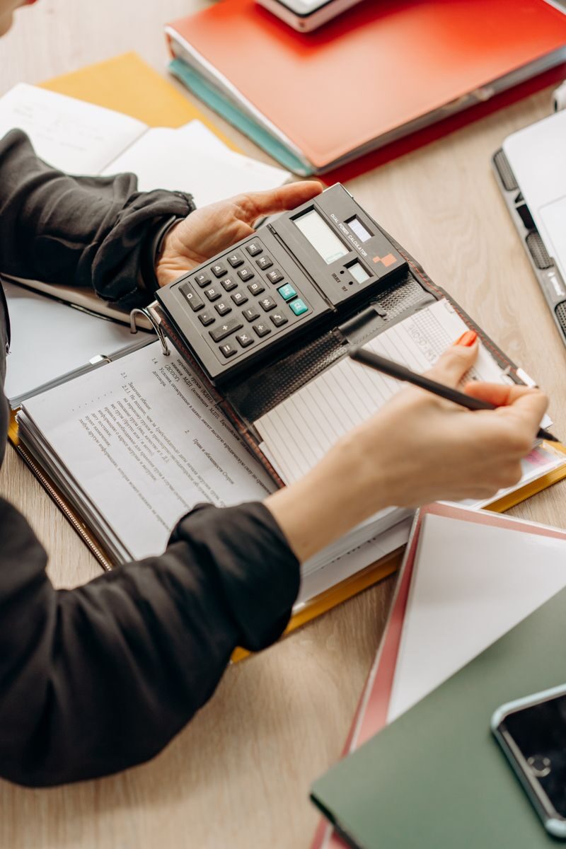 How to Choose the Right Business Loan for a One-Time Project Hands using a calculator during paperwork in an office setting. Ideal for business concept visuals.