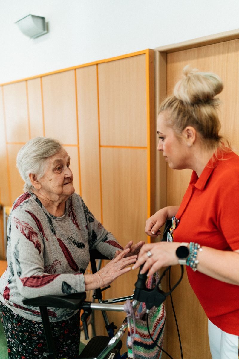 7 Best In-Home Care Services for Seniors in Dallas - Fort Worth (2026) A caregiver assists an elderly woman in a retirement home corridor, fostering companionship and support.