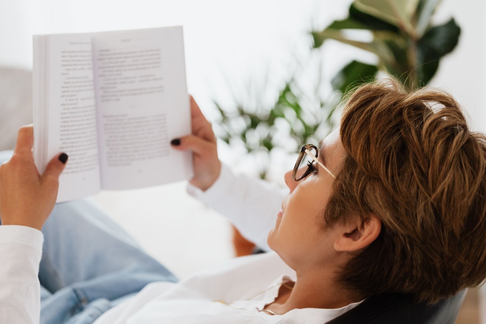 Tips for Building a Lifestyle Around the Things You Enjoy Side view of adult female in casual clothes and eyeglasses peacefully reading book with interest