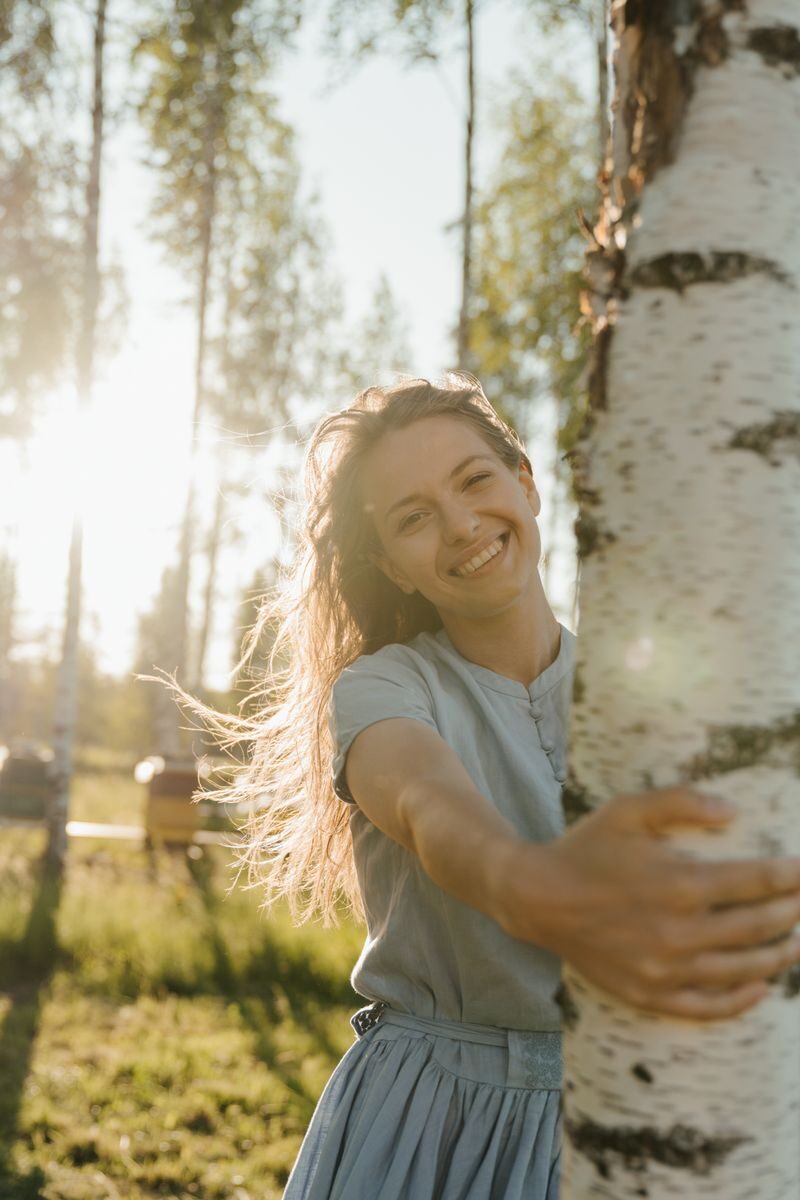 Tips for Building a Lifestyle Around the Things You Enjoy Smiling woman in a rural birch forest enjoying the summer sun.