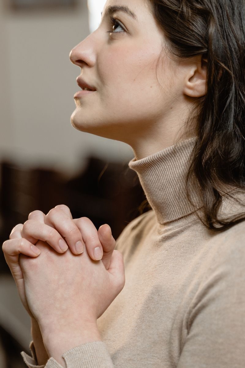 7 Best New Jersey Rehab Centers for Personalized Addiction Care (2026) Woman in a turtleneck praying with clasped hands, serene expression.