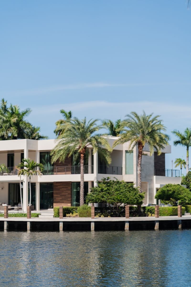 How Hiring Licensed Plumbers in Miami, FL Prevents Coastal Foundation Erosion Modern luxury villa by the waterfront surrounded by palm trees, under a clear blue sky.