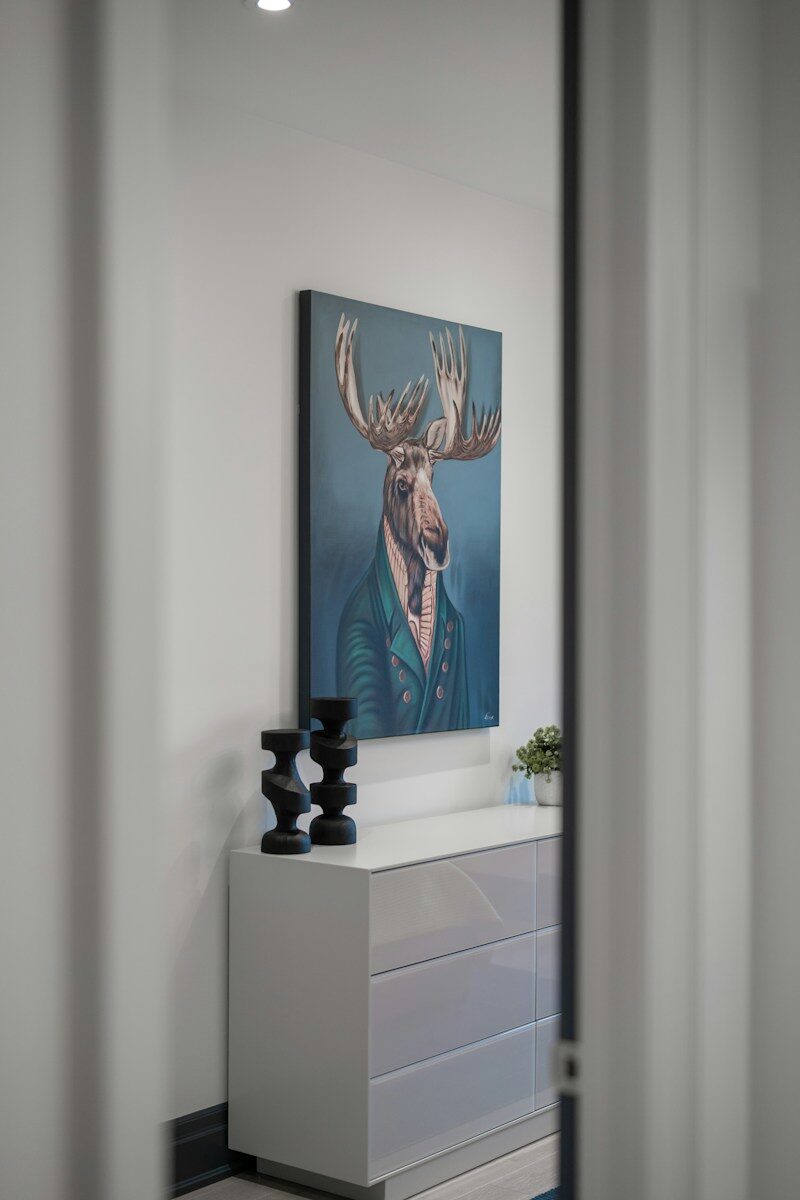 Animal art in cozy interior design Painting of a moose in a suit above a dresser