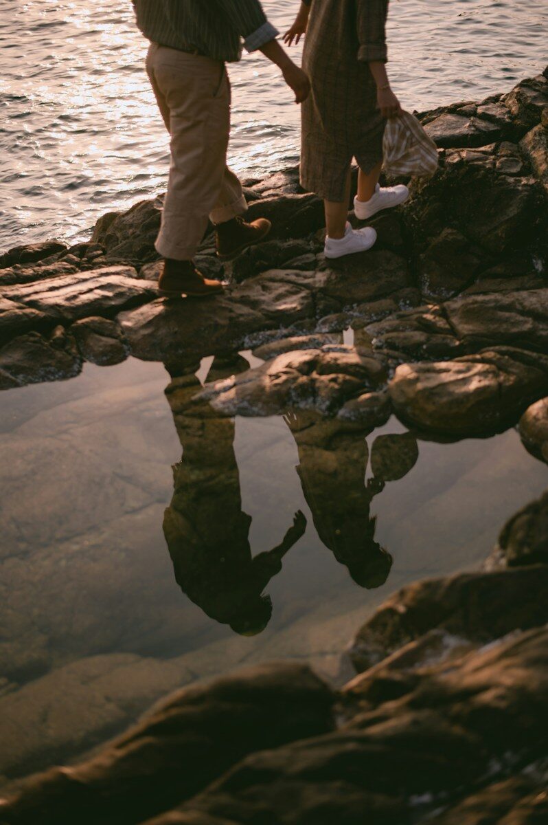 Relationship secrets Two people walking on rocky shore with their reflections in a tide pool