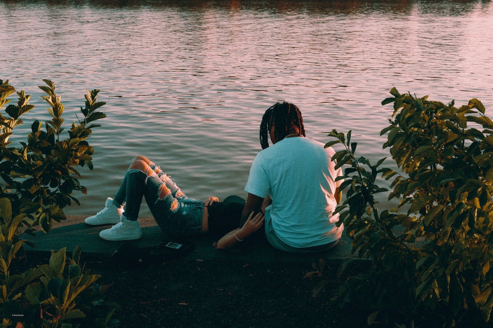 Relationship secrets Couple sitting by the water at sunset